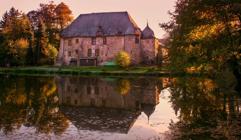 a large building sitting next to a body of water, by Josef Mánes, flickr, renaissance, autumn sunset, rennes - le - chateau, 2 4 mm iso 8 0 0, old castle