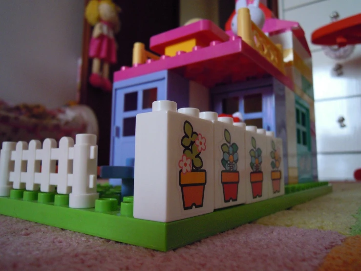 a toy house sitting on top of a rug, inspired by Derf, flickr contest winner, flower pots, lego set, [ closeup ]!!, pink white and green