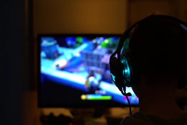 a person sitting in front of a tv wearing headphones, a screenshot, by Tom Carapic, pexels, happening, action game, gaming pc, focus in the foreground, from wow
