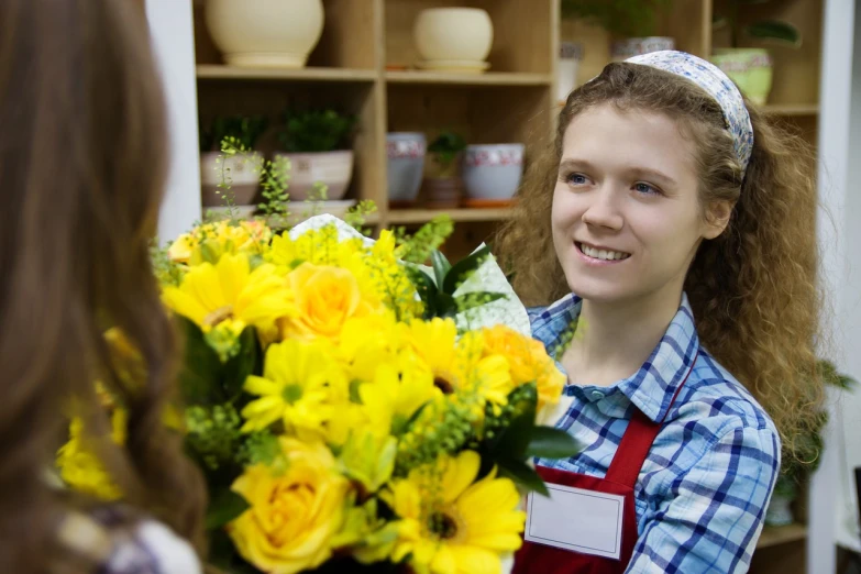 a woman holding a bouquet of yellow flowers, by Maksimilijan Vanka, shutterstock, ( waitress ) girl, flower shop scene, production still, teenage girl