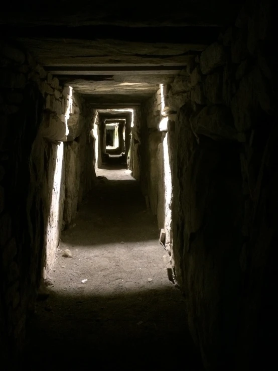 a dark tunnel with a light at the end, obelisks, celtic culture, barrows, wikimedia