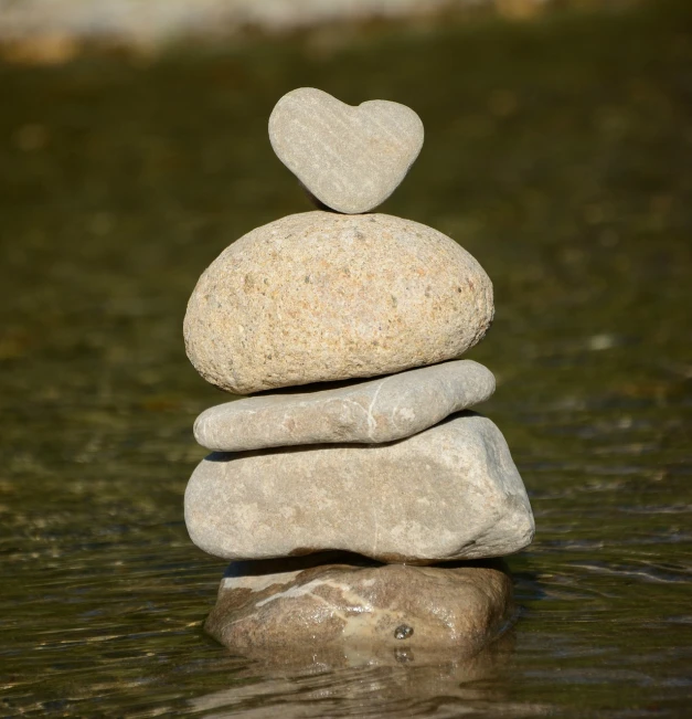 a stack of rocks sitting on top of a body of water, land art, hearts symbol, high detail product photo