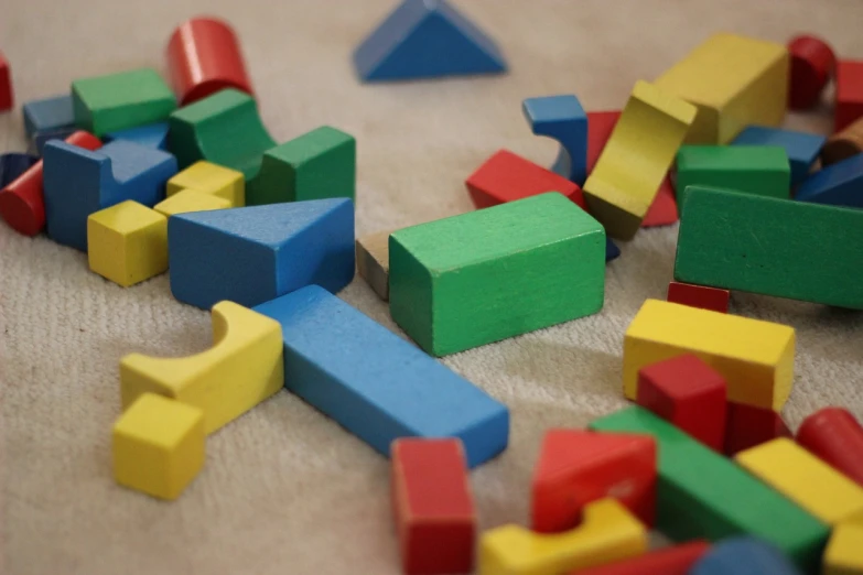 a pile of wooden blocks sitting on top of a table, a picture, constructivism, solid coloured shapes, broken toys, 2045