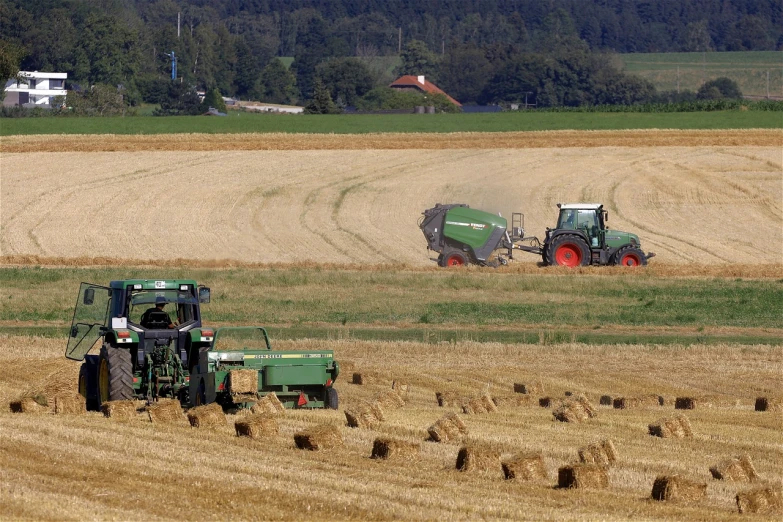 a couple of tractors that are in the grass, a picture, by Hans Schwarz, figuration libre, afp, fields in foreground, hay, ball