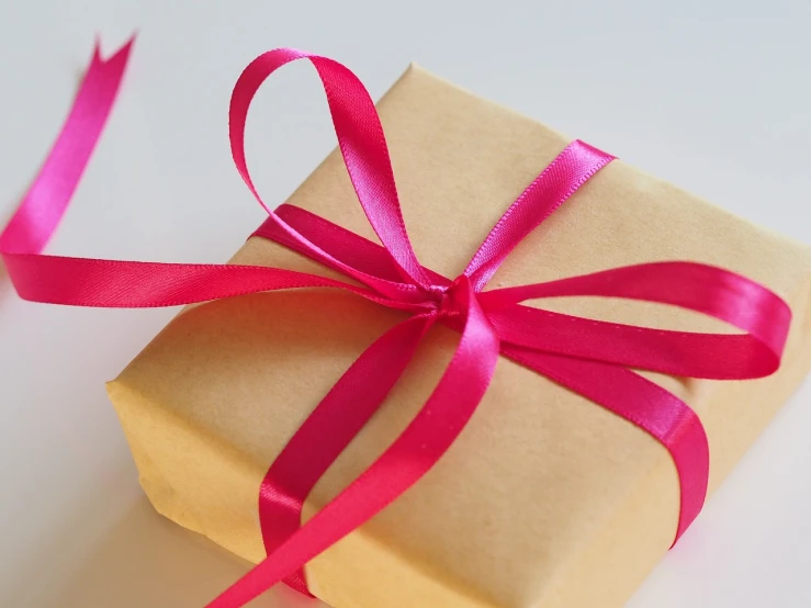 a gift wrapped in brown paper with a pink ribbon, by Maksimilijan Vanka, pixabay, pink hair bow, mobile wallpaper, 🎀 🧟 🍓 🧚, closeup - view