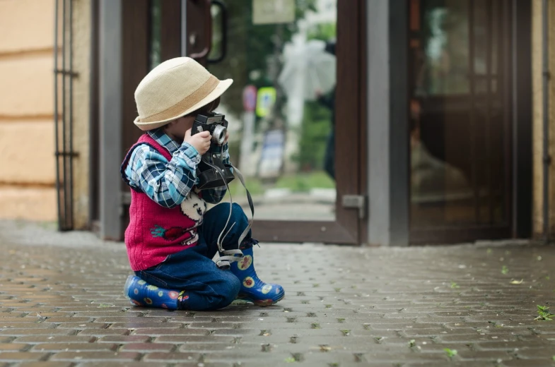 a little boy that is sitting down with a camera, inspired by Vivian Maier, pexels, photorealism, photorealism. trending on flickr, flickr explore 5 0 mm, tourist photo, cute:2