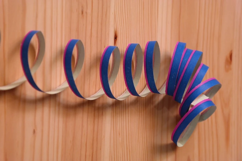 a close up of a pair of scissors on a wooden surface, an abstract sculpture, op art, blue and pink colors, paper decoration, worm, photo 3 d