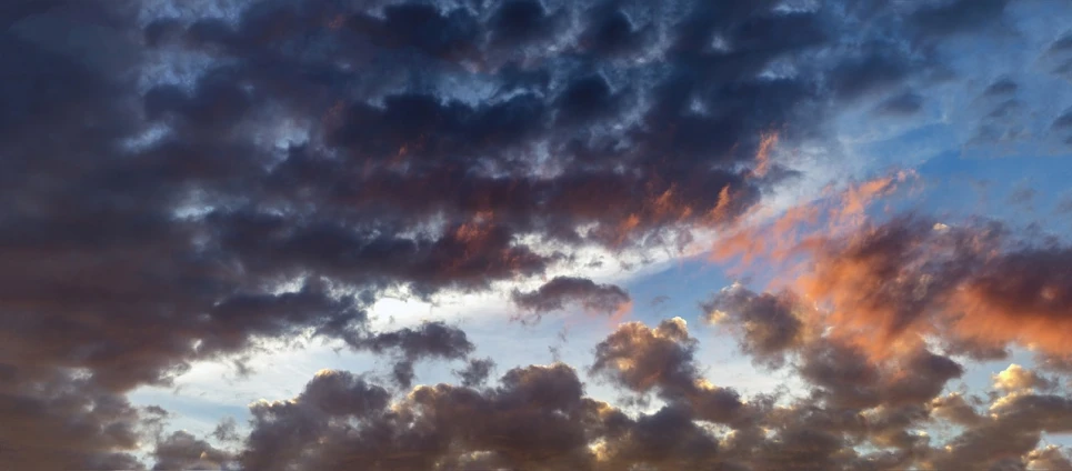 a plane flying through a cloudy sky at sunset, a picture, by Steven Belledin, shutterstock, layered stratocumulus clouds, dark storm clouds above, whorl. clouds, pink cloudy background