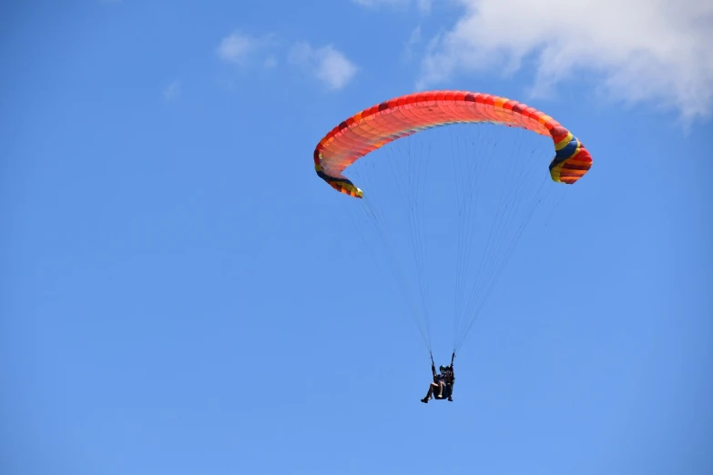 a person that is in the air with a parachute, clear blue skies, 3 4 5 3 1, view from the side, blue and red color scheme
