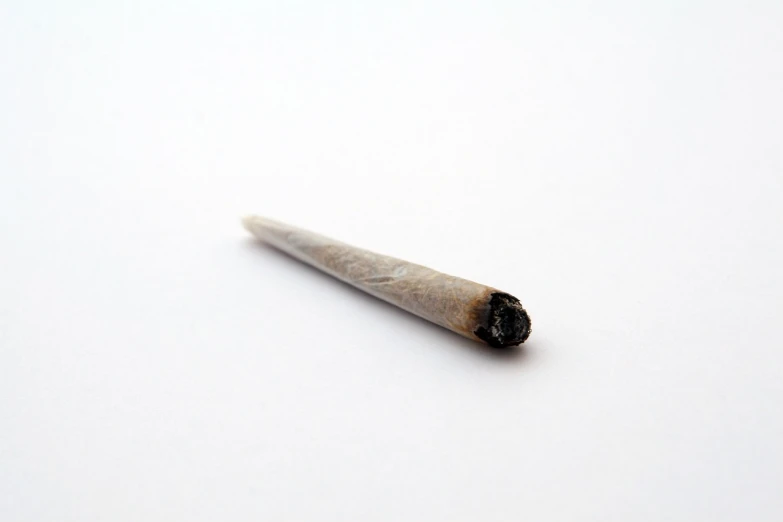 a close up of a cigarette on a white surface, hurufiyya, hemp, artifact, longspear, crystalline