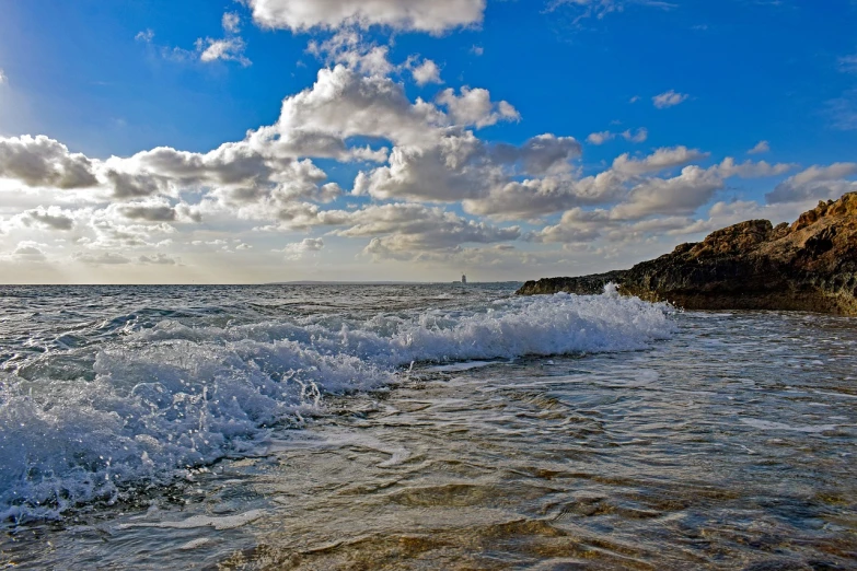 a man riding a surfboard on top of a wave in the ocean, a picture, by Dave Melvin, mediterranean beach background, hdr!, sparkling cove, clouds and waves