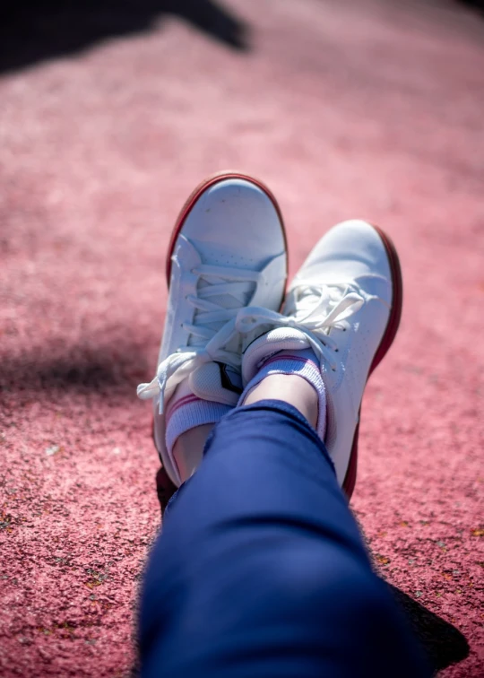 a close up of a person's feet on a red carpet, a picture, shutterstock, figuration libre, wearing white sneakers, with a park in the background, sigma 85/1.2 portrait, in an arena pit