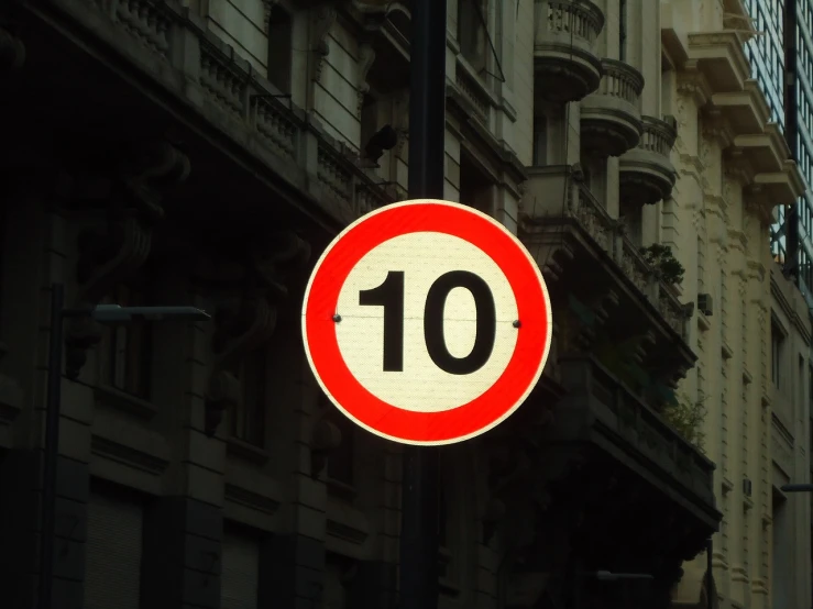 a close up of a street sign with a building in the background, a photo, by Pedro Álvarez Castelló, pixabay, ten flats, countdown, size 1 0, no helmet!!!!