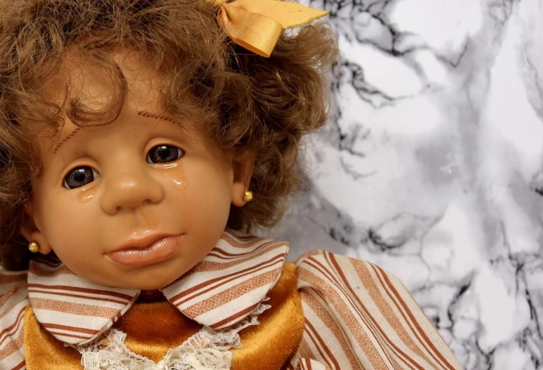 a close up of a doll wearing a dress, a portrait, inspired by Louis Le Nain, trending on pixabay, portrait of a crying ai artist, african american girl, caramel, 1986