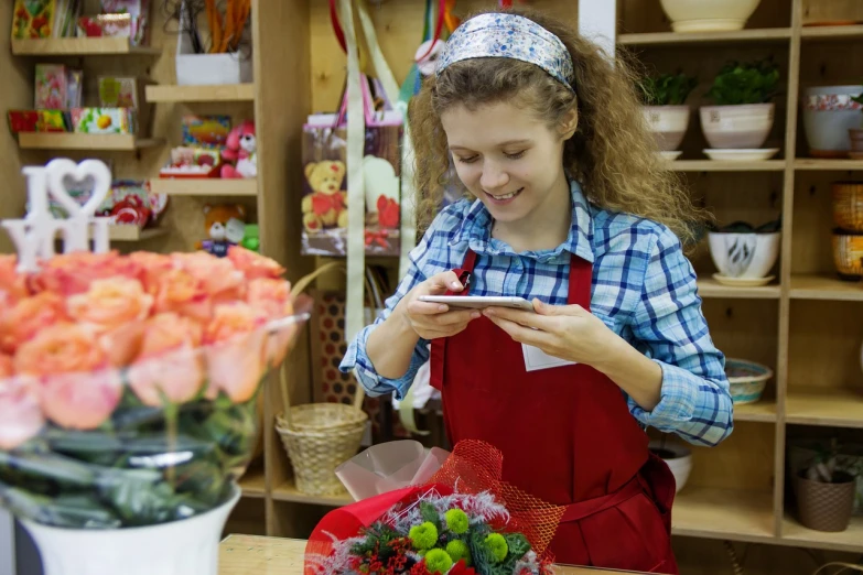 a woman in a flower shop looking at her phone, a stock photo, by Linda Sutton, shutterstock, ukrainian girl, teenager girl, roses in hands, maintenance photo