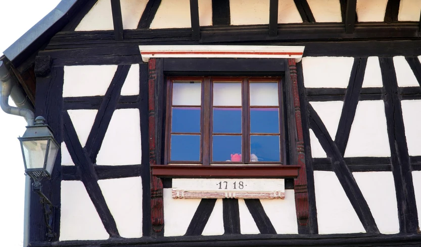 a clock that is on the side of a building, inspired by Matthias Jung, flickr, french village interior, tudor architecture, mid shot photo, bay window