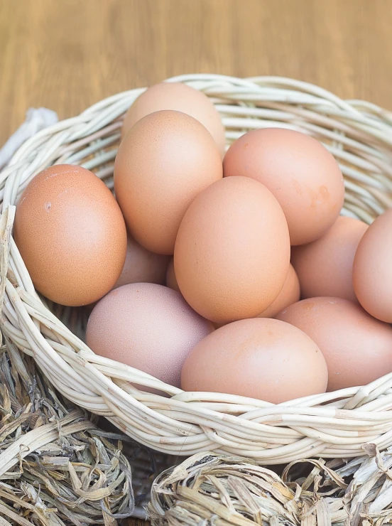 a basket filled with eggs sitting on top of a wooden table, a stock photo, by Juan O'Gorman, shutterstock, close up food photography, half image