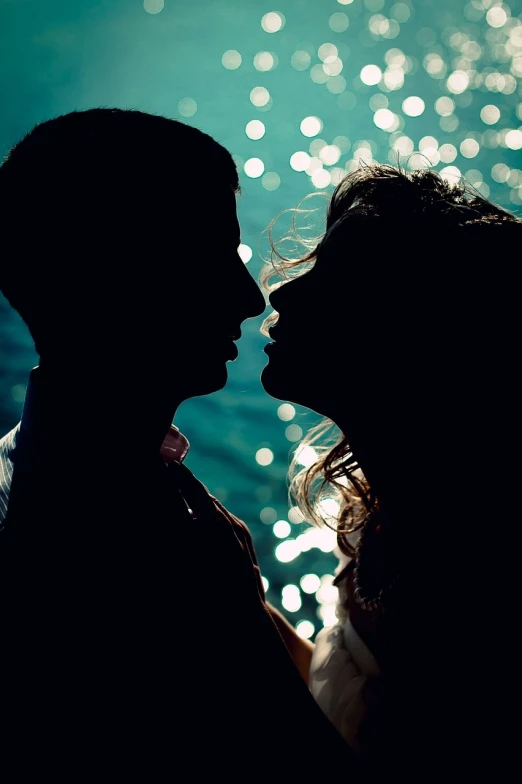 a couple standing next to each other in front of a body of water, a picture, tumblr, romanticism, kiss mouth to mouth, backlit glow, dasha taran, siluette