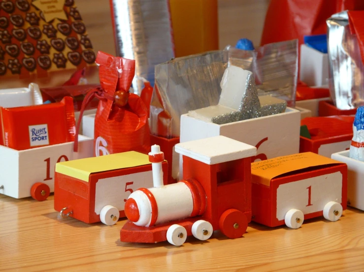 a close up of a toy train on a table, by Zsuzsa Máthé, flickr, dressed in red paper bags, countdown, cigarrette boxes at the table, different sizes