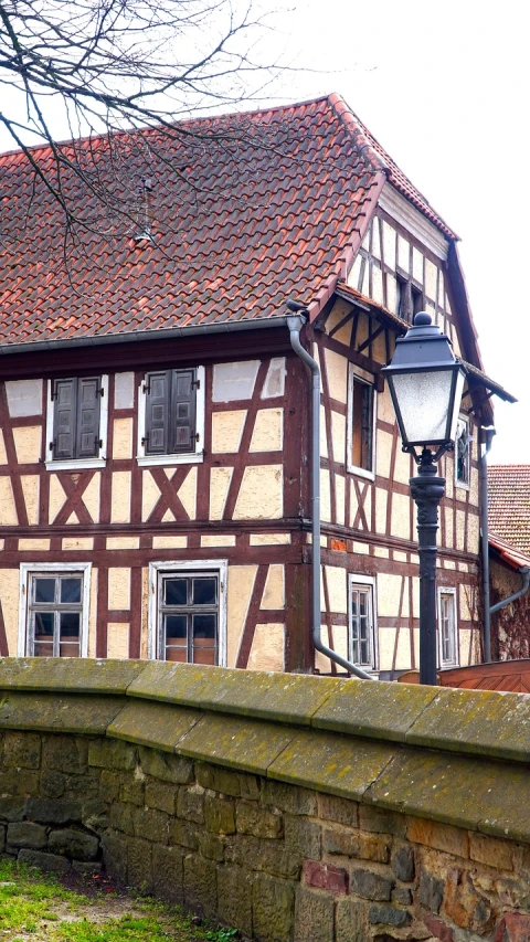 a brown and white house next to a stone wall, a photo, by Karl Hagedorn, renaissance, beams, hannover, medieval city, high detaild