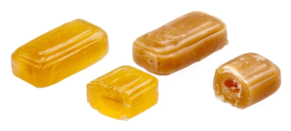 three pieces of caramel sitting next to each other, dau-al-set, transparent, yellowed, wax, chewing