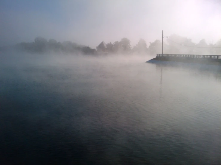 a boat in a body of water on a foggy day, a picture, flickr, hurufiyya, espoo, terrifying!!!, rising steam, a photo of a lake on a sunny day