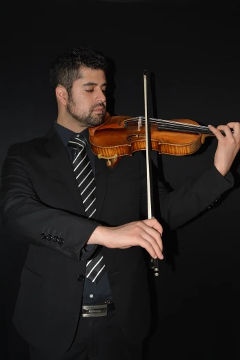 a man in a suit playing a violin, inspired by Nadim Karam, flickr, standing with a black background, 3 / 4 view portrait, meni chatzipanagiotou, recital