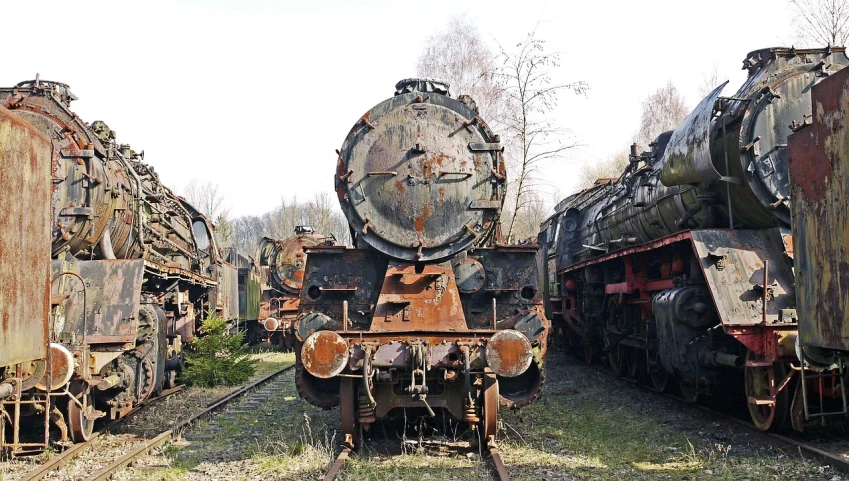a group of old trains sitting next to each other, by Jacek Sempoliński, auto-destructive art, rear view, circular face, looming head, lower saxony