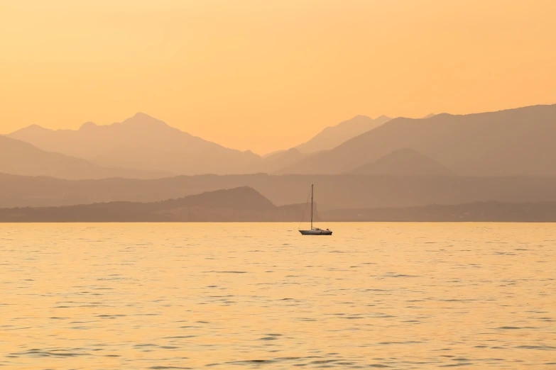 a boat floating on top of a large body of water, by Alexis Grimou, pexels contest winner, romanticism, pastel palette silhouette, bronze!! (eos 5ds r, mountains in distance, pale orange colors