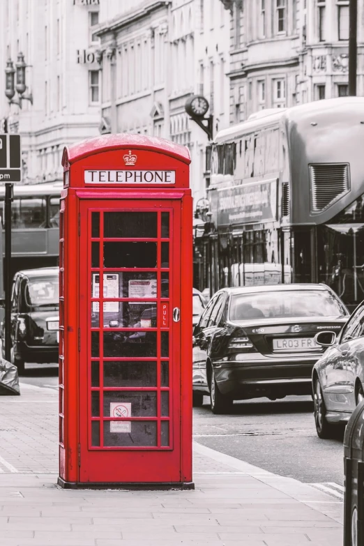 a red telephone booth sitting on the side of a street, a picture, shutterstock, fine art, red and black and white, london streets in background, 🐝👗👾, red car