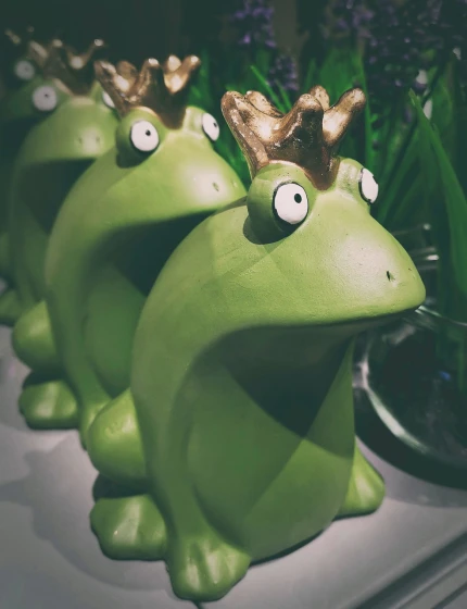 three green frogs with crowns on their heads, inspired by Jeff Koons, pexels, animal - shaped cake, nicolas cage mossy statue, retro stylised, moomins