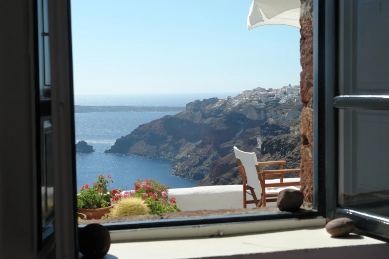 a cat sitting on a window sill looking out at the ocean, a picture, romanticism, in santorini island, small cottage in the foreground, summer 2016, sheer cliffs surround the scene