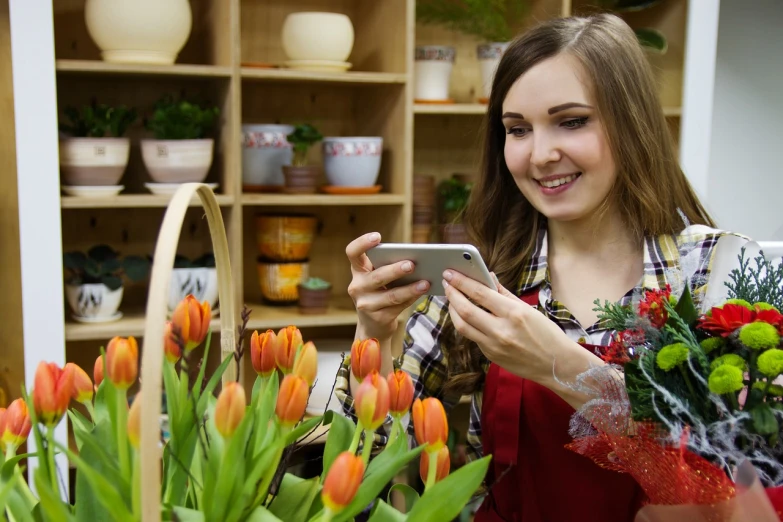 a woman in a flower shop looking at her phone, a picture, by Arthur Sarkissian, shutterstock, tulips, attractive girl, professional photo, product introduction photo