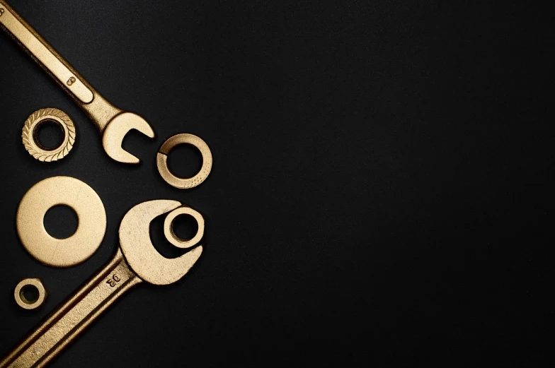 a group of tools sitting on top of a black surface, by Andrei Kolkoutine, trending on pexels, art nouveau, wrench, white and gold color scheme, website banner, high resolution product photo