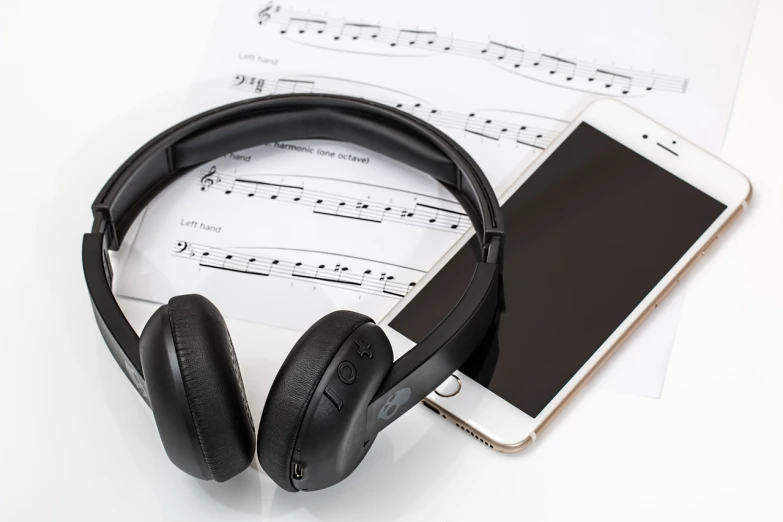 a pair of headphones sitting on top of a sheet of music, pixabay, phone, set against a white background, high-tech devices, an instrument
