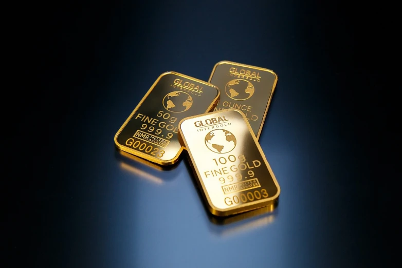 a couple of gold bars sitting next to each other, a picture, high quality product photography, on a reflective gold plate, blue gold and black, coin