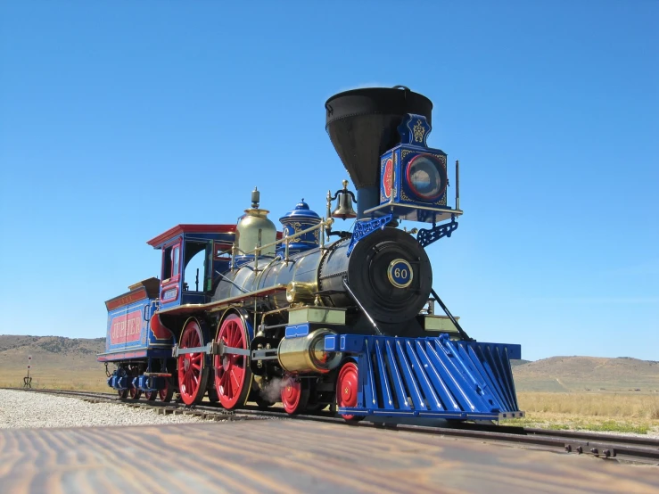 a blue and red train traveling down train tracks, a portrait, brass and steam technology, replica model, on the desert, super-realistic