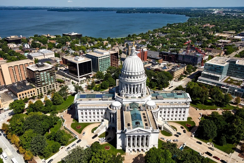 a large white building sitting on top of a lush green field, by Greg Rutkowski, shutterstock, aerial view of a city, wisconsin, rotunda, jessica