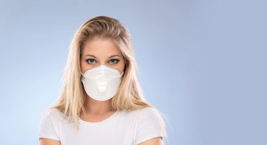 a woman wearing a face mask on a blue background, by Konrad Witz, shutterstock, plasticien, young blonde woman, dressed in a white t shirt, bag - valve mask, in front of white back drop