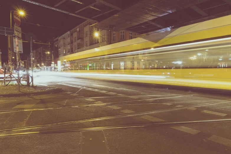 a city street at night with a bus passing by, a picture, by Thomas Häfner, happening, yellow lightning, retro effect, berlin, panning shot