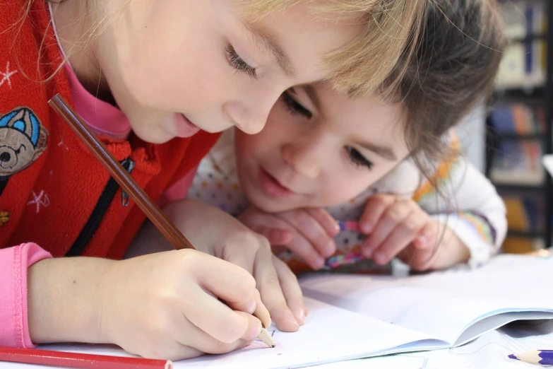 a couple of kids that are sitting at a table, a child's drawing, by Samuel Scott, pexels, visual art, two girls, beautiful angle, drawing sketches on his notebook, closeup - view