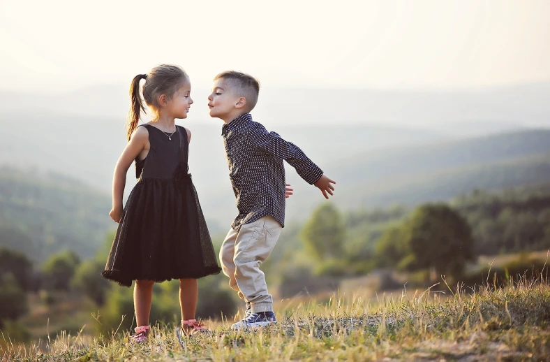a couple of kids standing on top of a grass covered hillside, a picture, pexels, romanticism, peasant boy and girl first kiss, black, (beautiful) girl, dialog