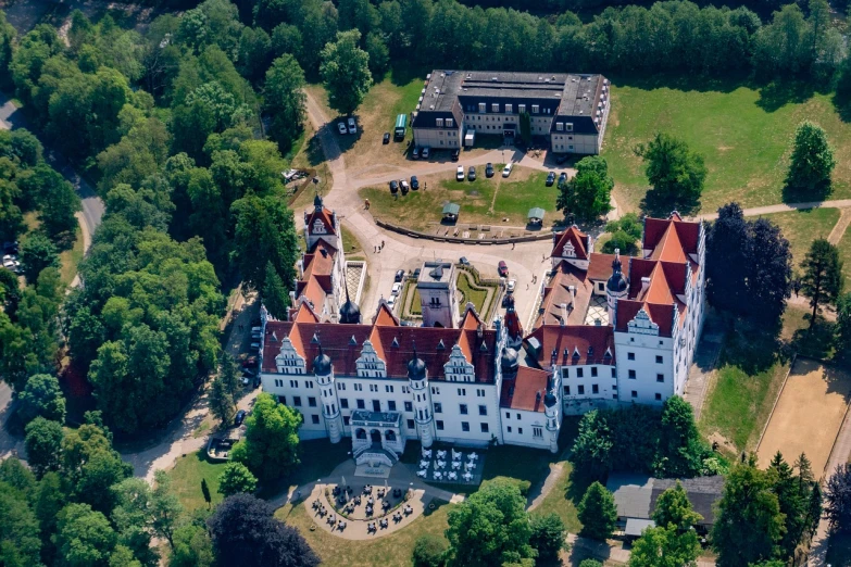 an aerial view of a castle surrounded by trees, a portrait, by Dietmar Damerau, shutterstock, white buildings with red roofs, high quality photo, movie set”, concert