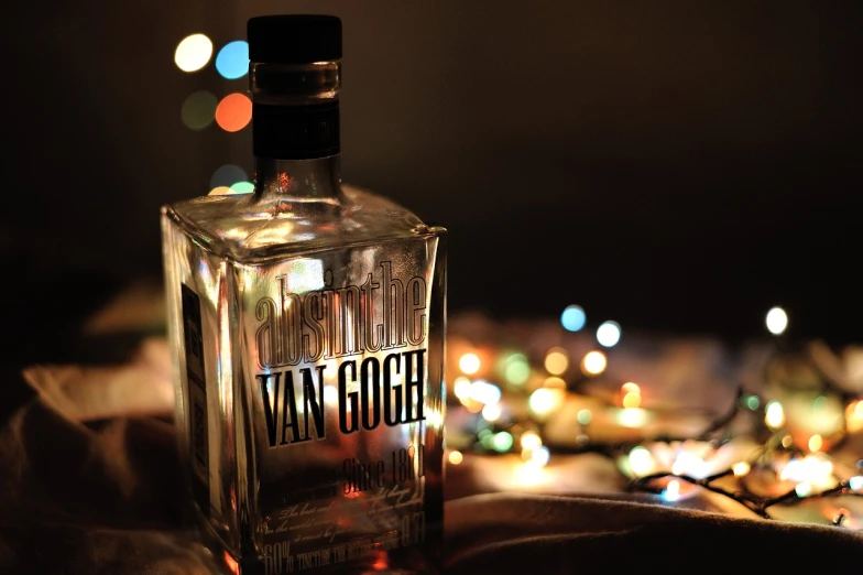 a bottle of vodka sitting on top of a bed, a tilt shift photo, by Hugo van der Goes, tumblr, vanitas, goodnight, with lots of glittering light, label, vaughan bass