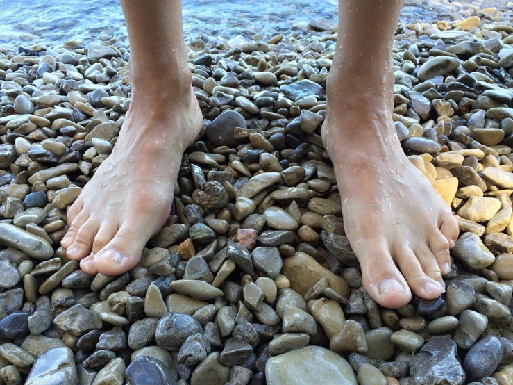 a person standing on some rocks by the water, by Jan Rustem, hyperrealism, exposed toes, hyperrealistic!, professional foot photography, realistic!