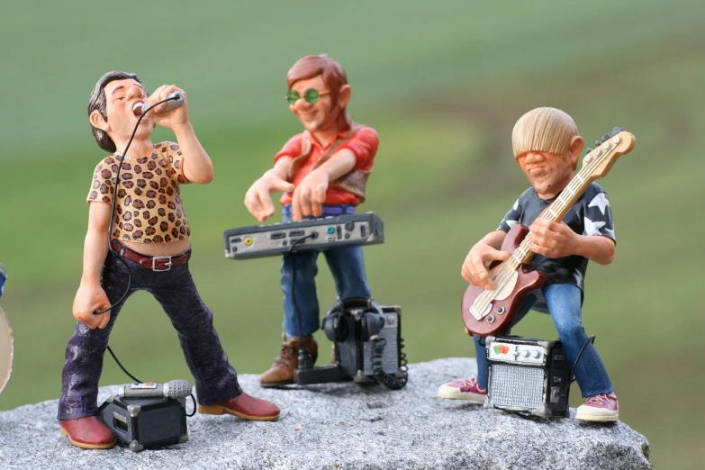 a group of figurines sitting on top of a rock, inspired by Kurt Wenner, trending on pixabay, figuration libre, performing a music video, toy photo, rocking out, 3 actors on stage