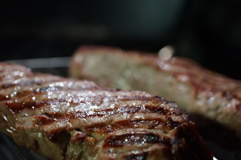 a close up of some meat on a grill, a picture, by Tom Carapic, a pair of ribbed, with dramatic lighting, made of glazed, side-view