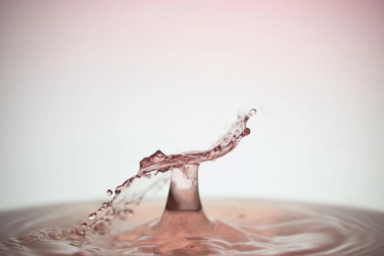 a splash of water on top of a table, minimalism, light pink background, very sharp photo