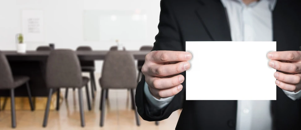 a man in a suit holding a piece of paper, a picture, pexels, private press, cubical meeting room office, background image, low resolution, background bar