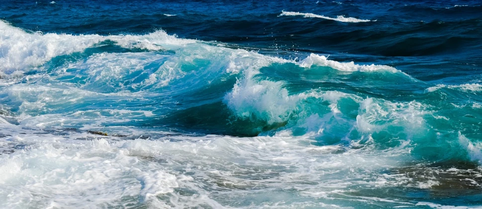 a man riding a wave on top of a surfboard, a picture, by Alexander Bogen, shutterstock, fine art, deep blue sea color, waves crashing at rocks, glistening seafoam, closeup!!